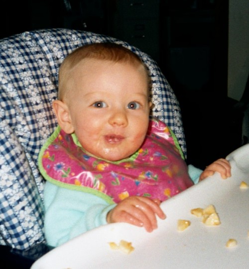 Annabelle eating messily in her highchair.